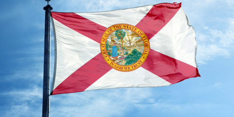 The Florida state flag waving against a blue sky.